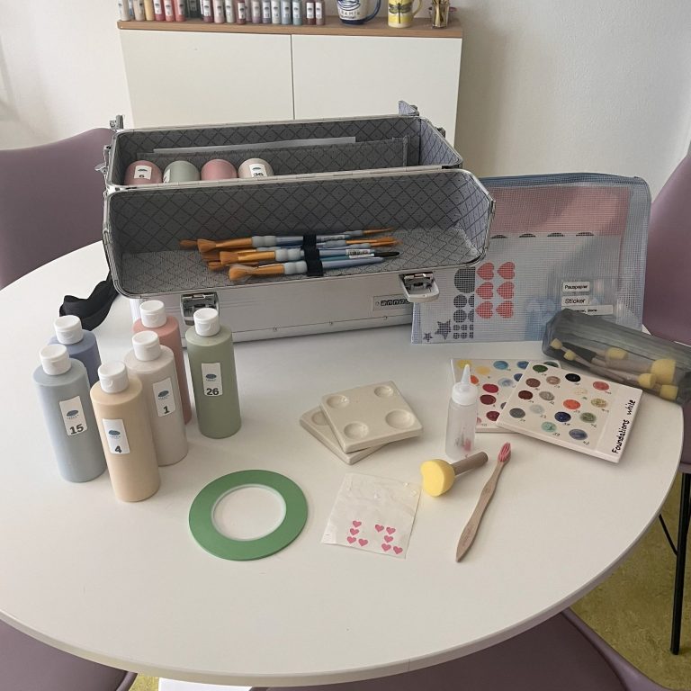 Werkzeugkiste mit Malutensilien wie Pinseln, Farben, Aufklebern und Schwämmen.