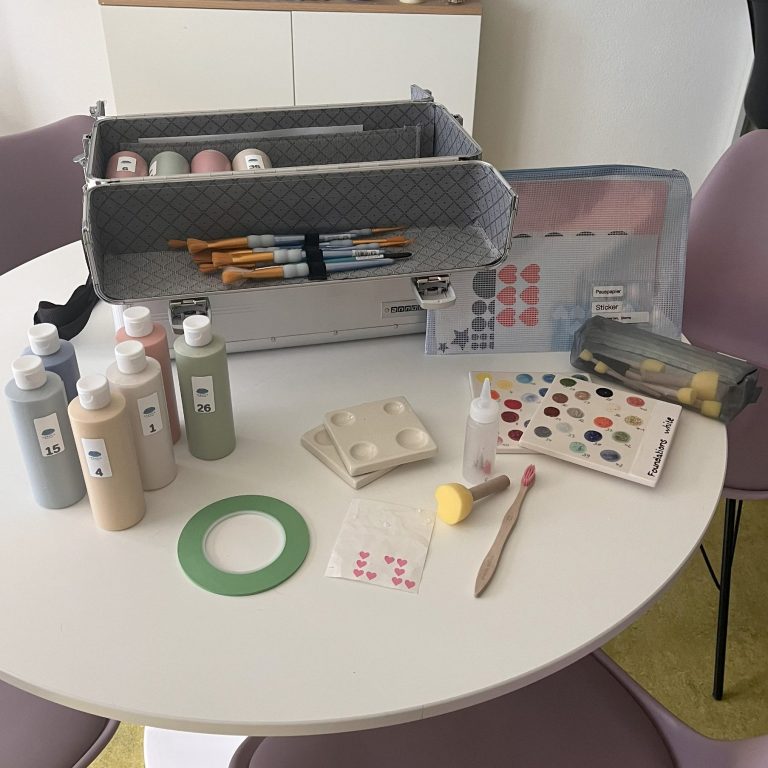 Werkzeugkiste mit Malutensilien wie Pinseln, Farben, Aufklebern und Schwämmen.